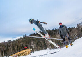 Larry Stone. NYSEF ski jumping coach with his group of young jumpers at Lake Placid NY's ski jumping complex. Photo might also just be young jumpers in action or at the top of the inrun without Larry. photo by Nancie Battaglia
